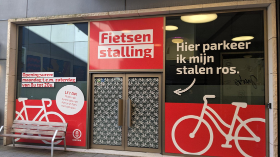 De ramen van de fietsenstalling zijn bekleefd met rode stickers. Op de stickers staan witte fietsen afgebeeld