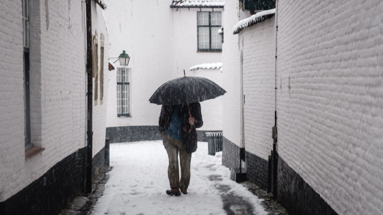 Man loopt in begijnhof tijdens sneeuwbui