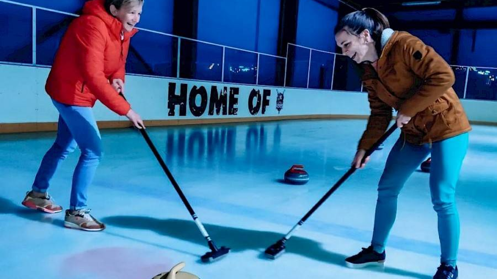 Twee mensen op het ijs die aan curling doen