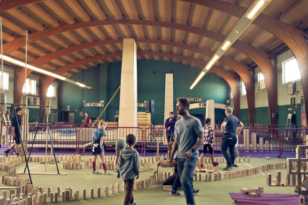 Mensen lopen rond in zaal waar dominoblokjes zijn opgesteld